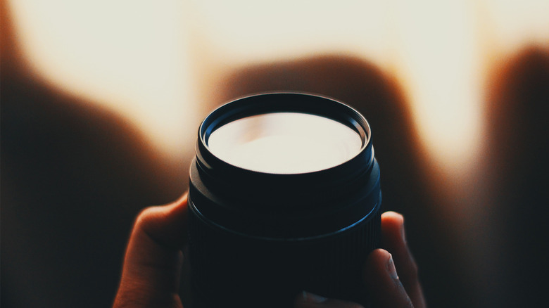 Person holding a camera lens