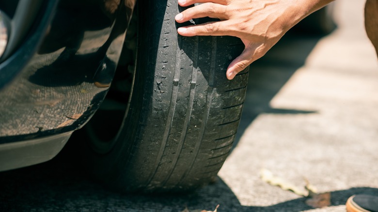 Man checking the tires on an old car