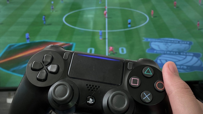 person holding PS4 controller playing FIFA