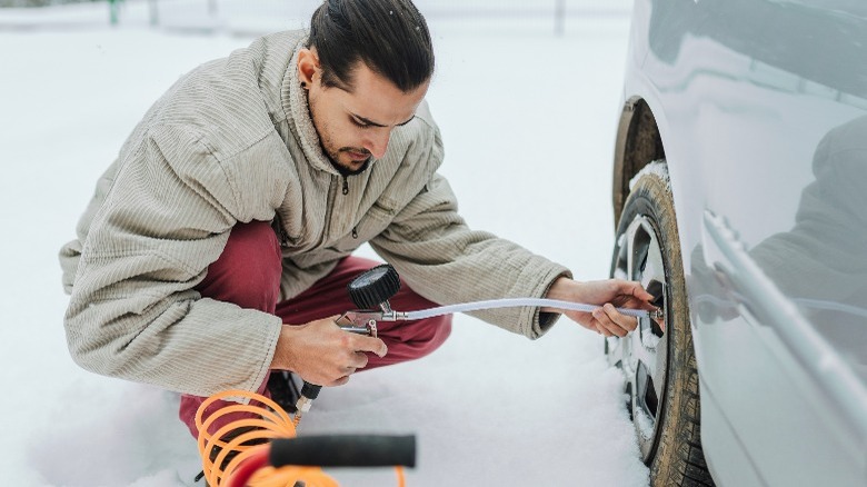 Man filling tire with air in the snow