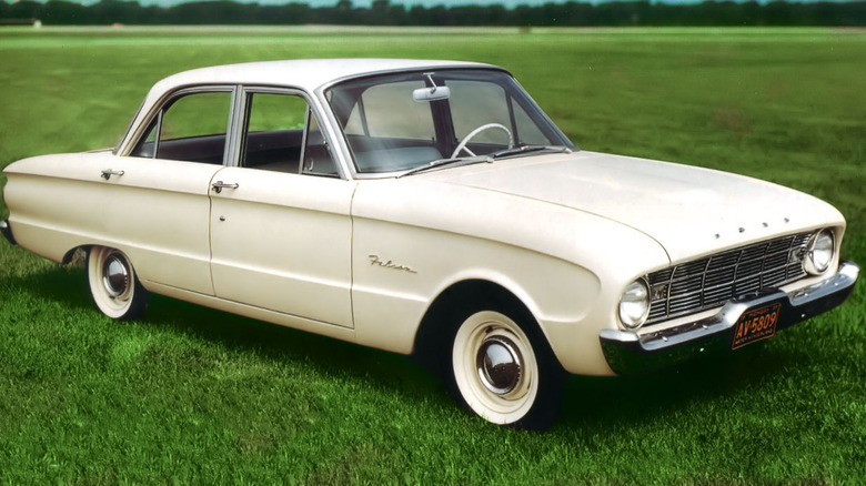 An eggshell white Ford Falcon parked in a grass field.