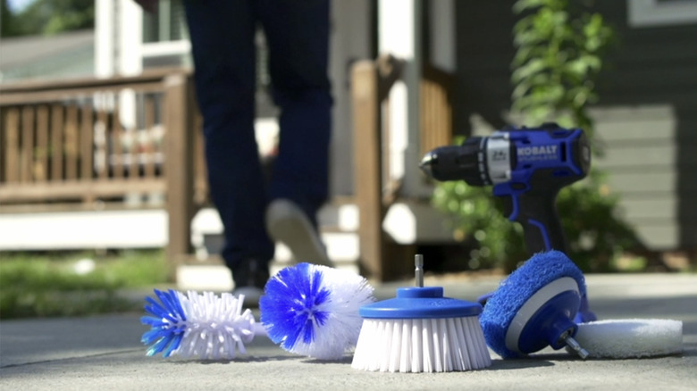 Scrub brush attachments sitting infront of drill on the ground outside