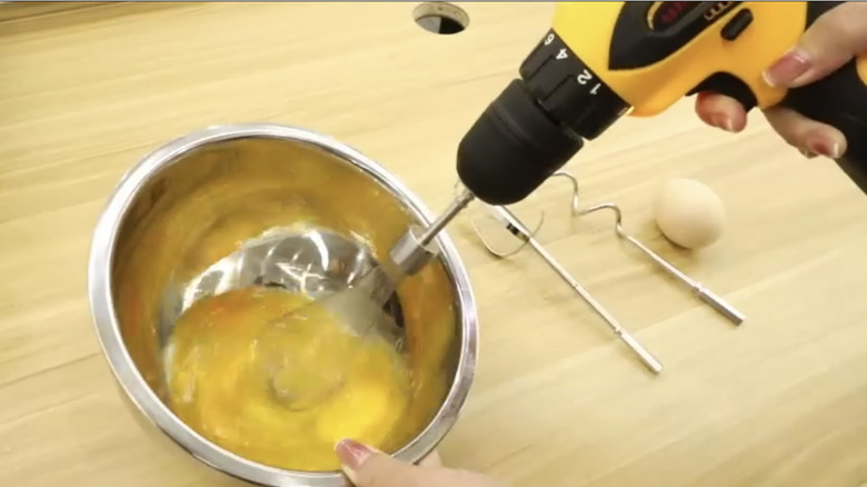 Person using a drill and a whisk attachment to beat eggs