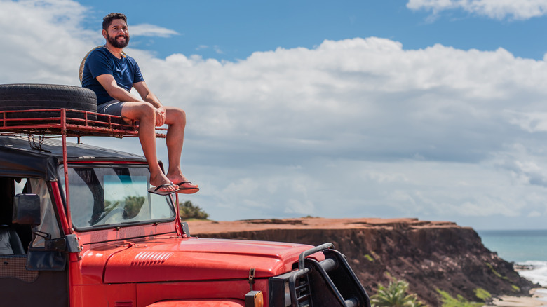 Man sitting on top of red Jeep