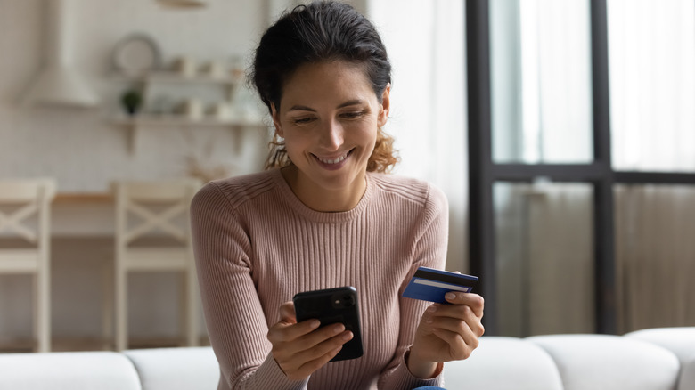 Woman holding a phone and a debit card