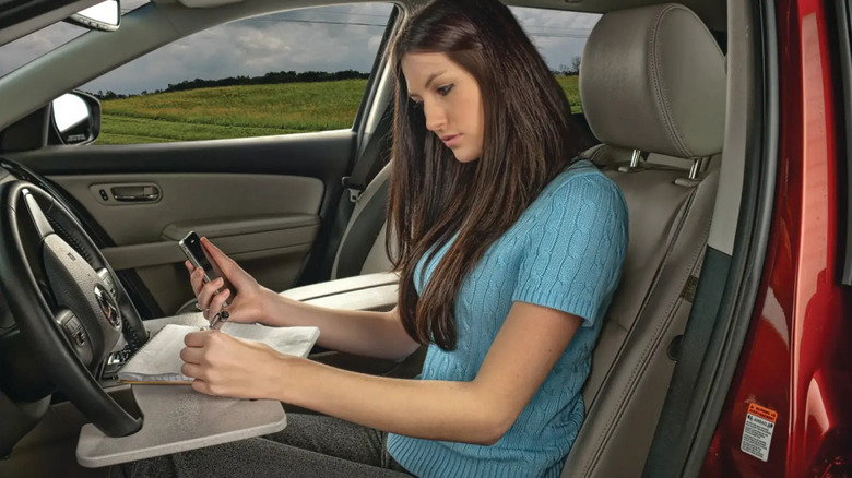 Girl sitting in a car with a wheel tray attached to the steering wheel