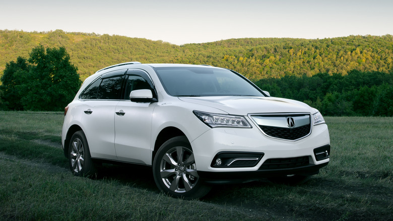 Acura on road surrounded by fields