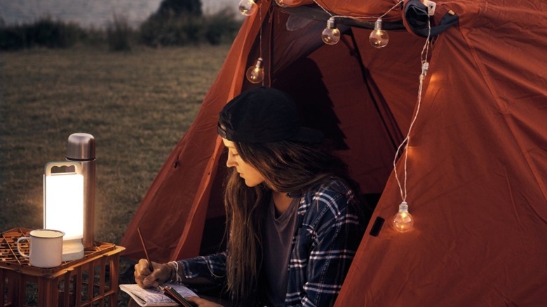 Girl in tent writing in journal