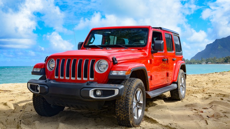 red Jeep Wrangler parked on beach