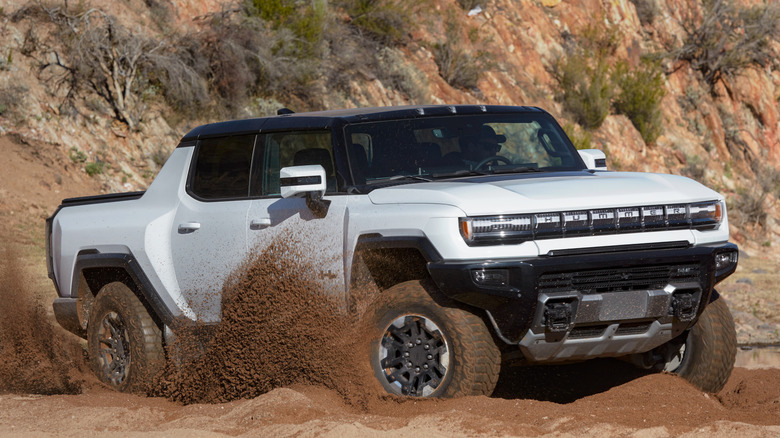 Front 3/4 view of GMC Hummer EV Pickup powering through dirt