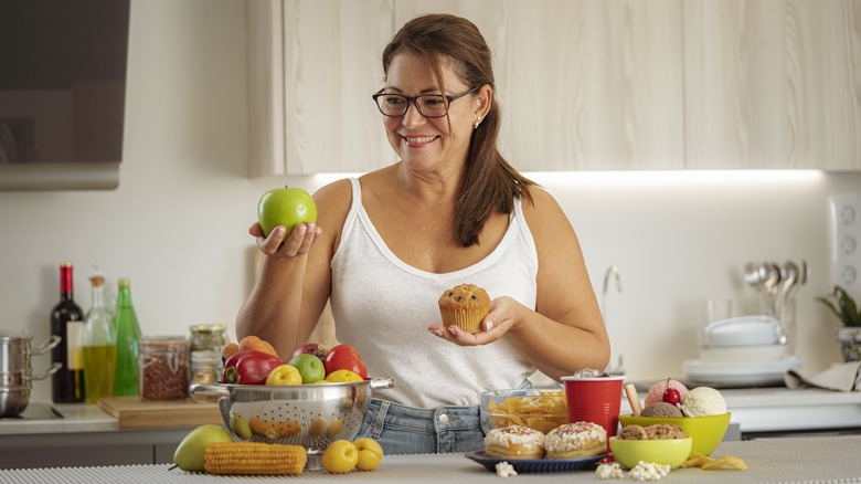 woman choosing between apple or muffin