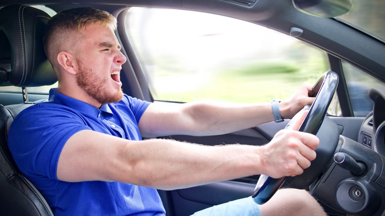 driver blue shirt screaming behind the wheel