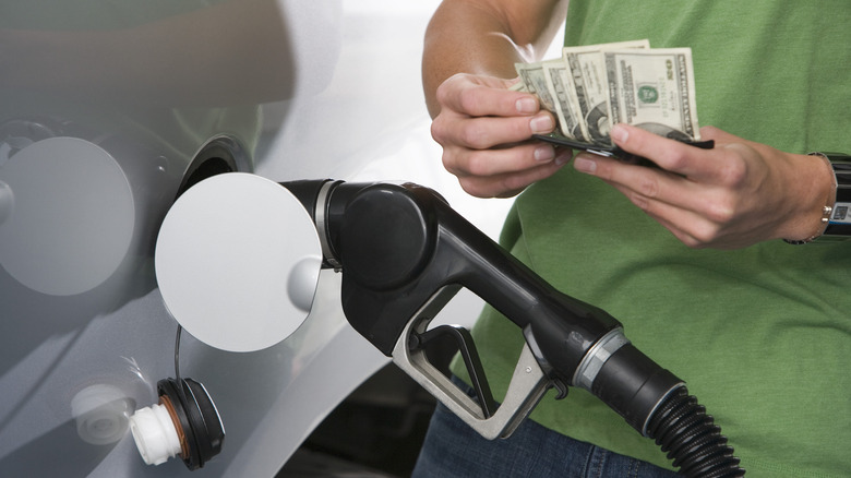 person counting money while pumping gas