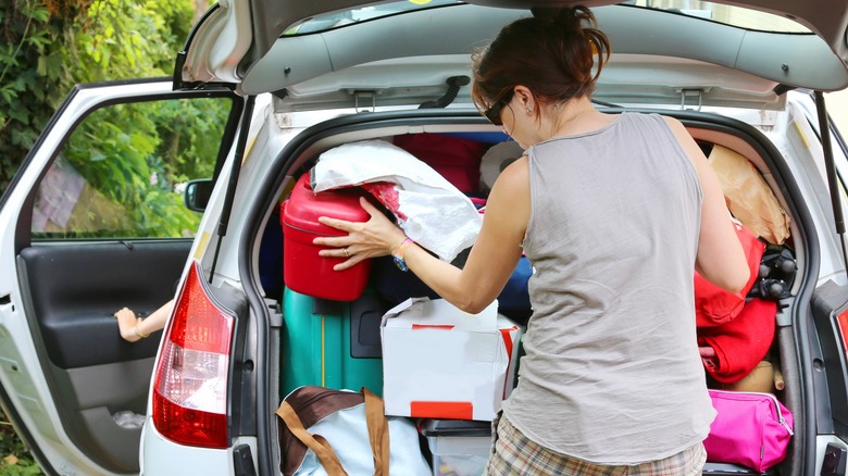 woman cramming items into overloaded vehicle