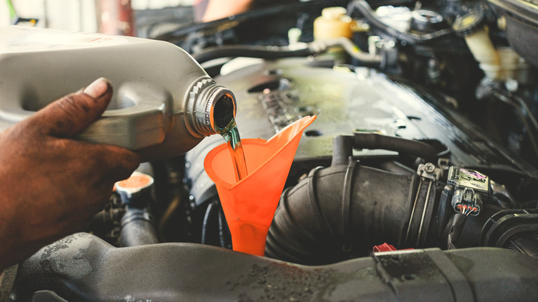 Hand pouring transmission fuild into car