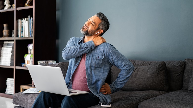 man with laptop on his laps stretches back