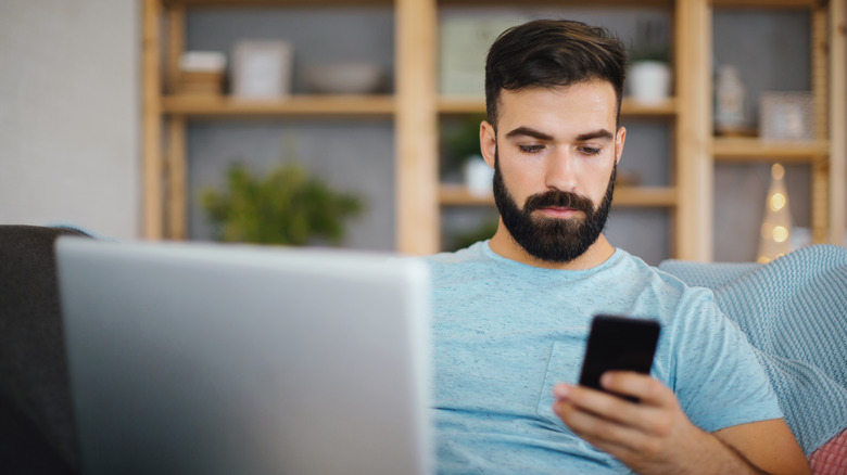 man using a smartphone and laptop 