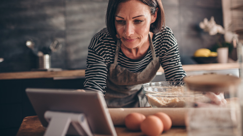 woman touching tablet while cooking