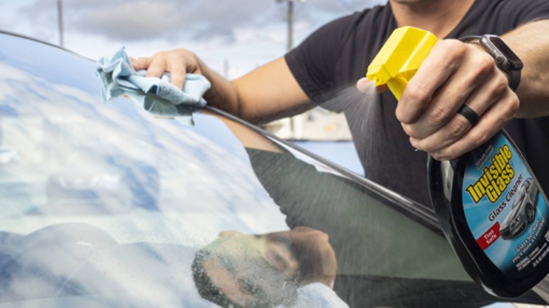 Man spraying a car's windshield