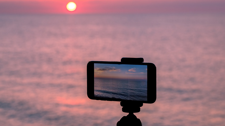 smartphone getting shot of the ocean sunset