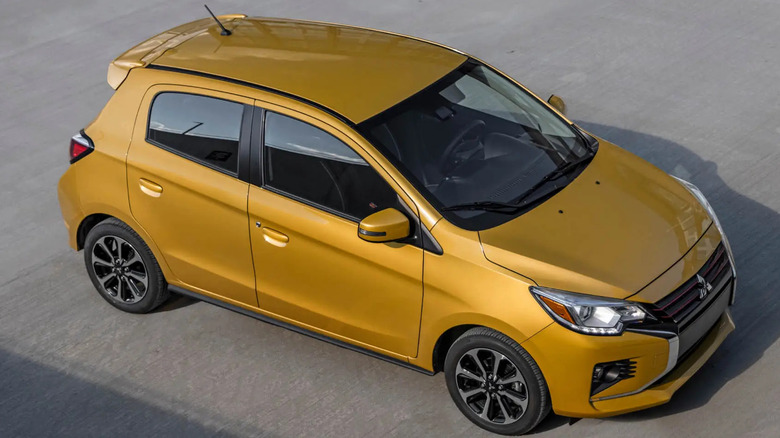 Yellow Mitsubishi Mirage parked on cement plaza