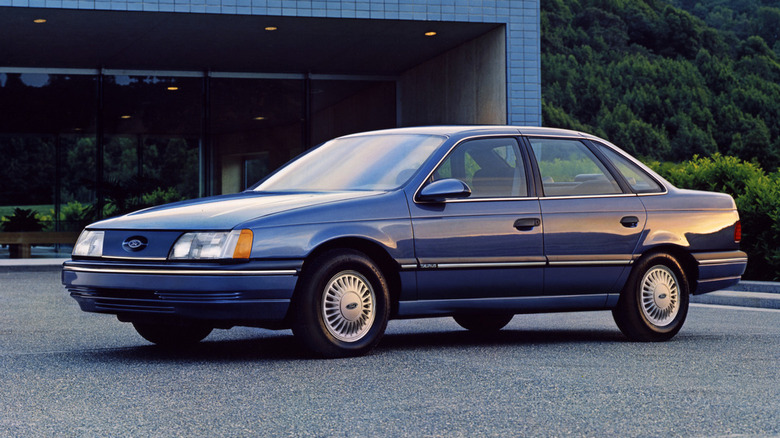 A blue 1986 Ford Taurus at sunset.