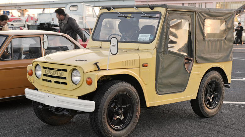 Yellow Suzuki Jimny with black canvas top in parking lot