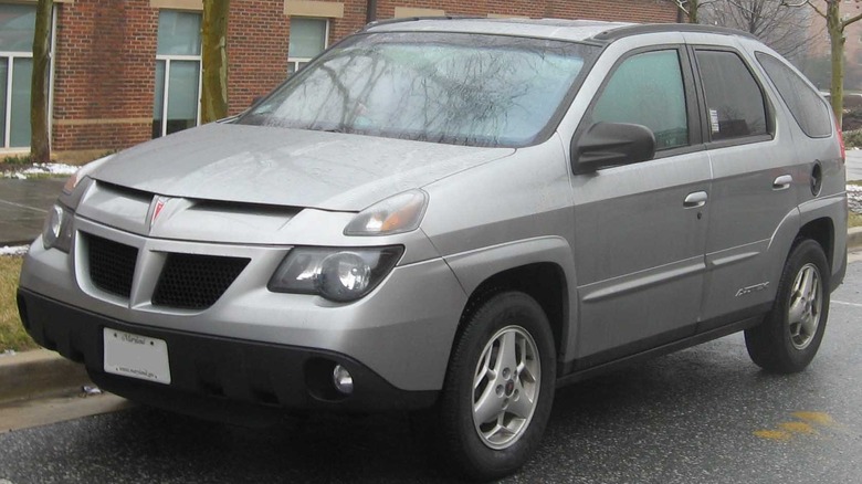 SIlver Pontiac Aztek parked on street in front of brick building