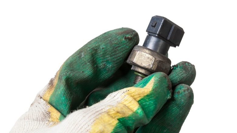 person holding an oil pressure sensor