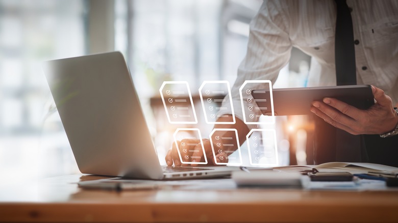 man using laptop with document icons