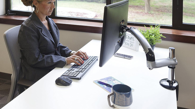 person looking at desk mounted monitor