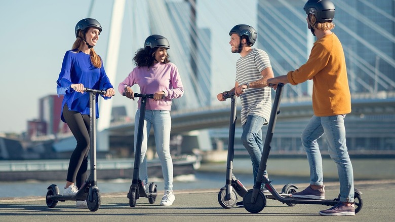 A group of people standing with Segway scooters