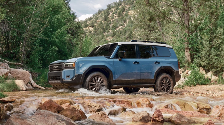 Blue Toyota Land Cruiser parked on mountain with front wheels in running stream