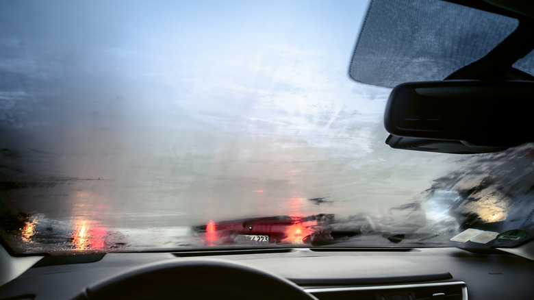 A foggy car windshield with brake lights shining through