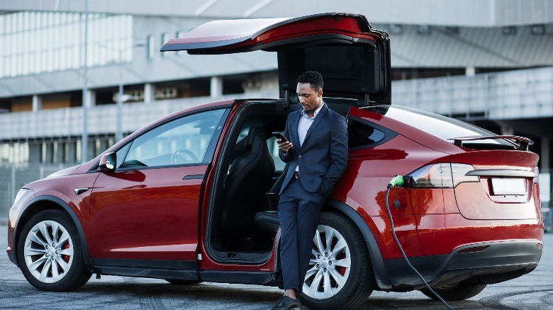 A man leaning on his EV while it's charging