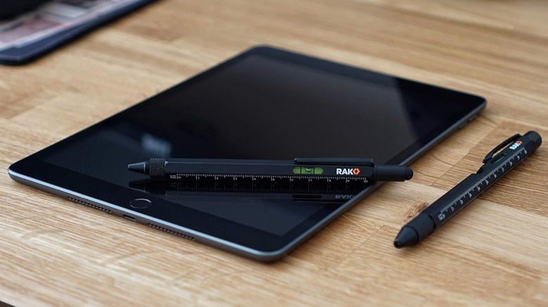 Two black Rak multitool pens, one of them lying atop a tablet computer