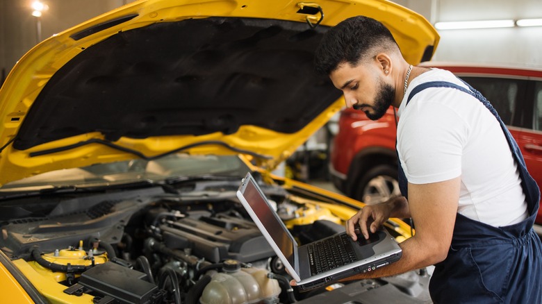 Man with laptop in front of car