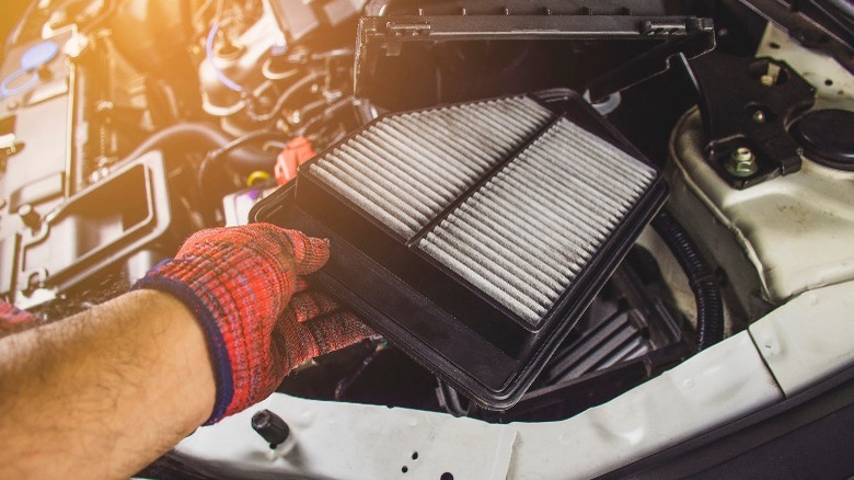 person replacing an engine air filter