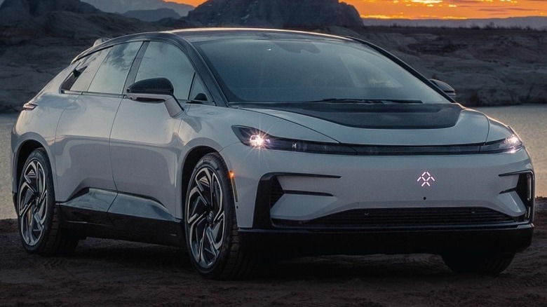 white Faraday Future FF 91 2.0 Futurist Alliance parked near a water body with mountains in the background