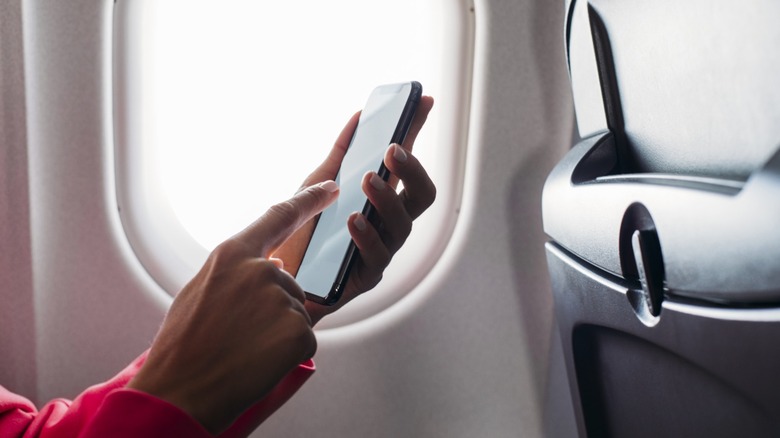 A passenger using smartphone on airplane