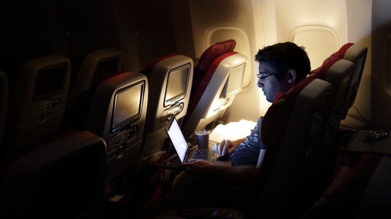 A passenger using a laptop on an airplane