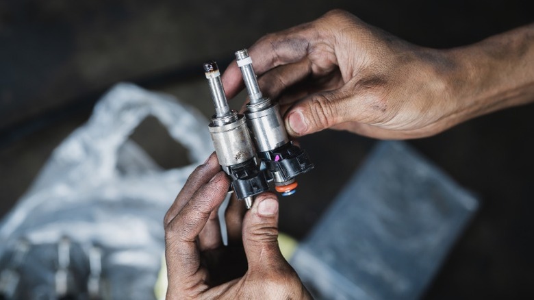 Mechanic holding new and old fuel injectors