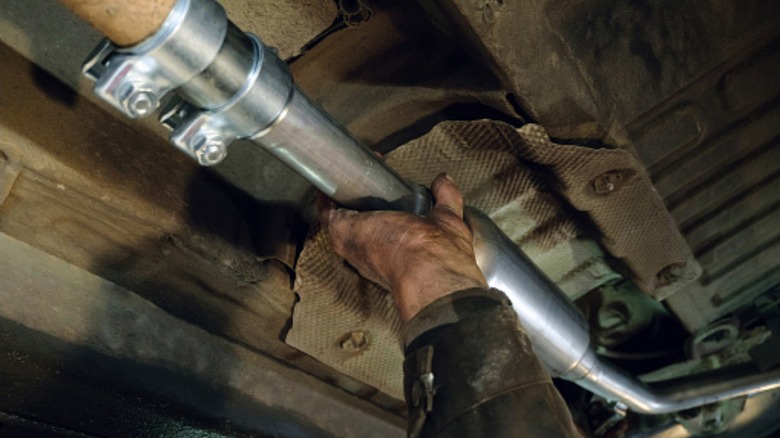 Mechanic installing new exhaust pipe