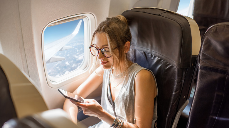 woman holding phone while on the plane