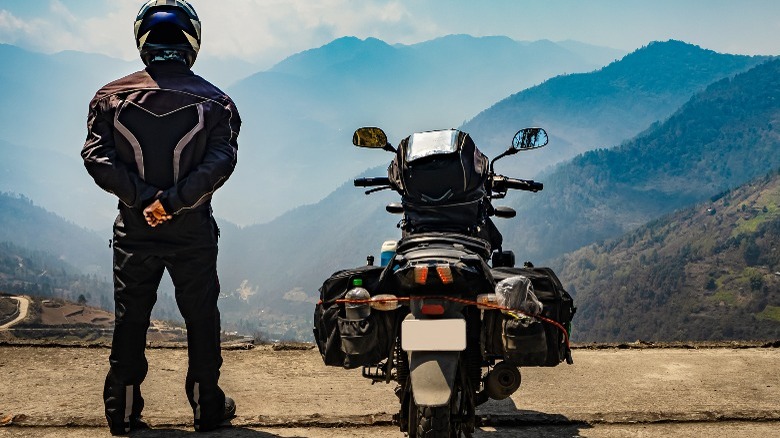 Man in motorcycle gear looking a the mountains