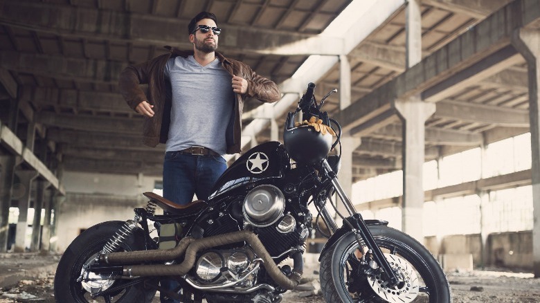 Man putting on jacket in front of motorcycle