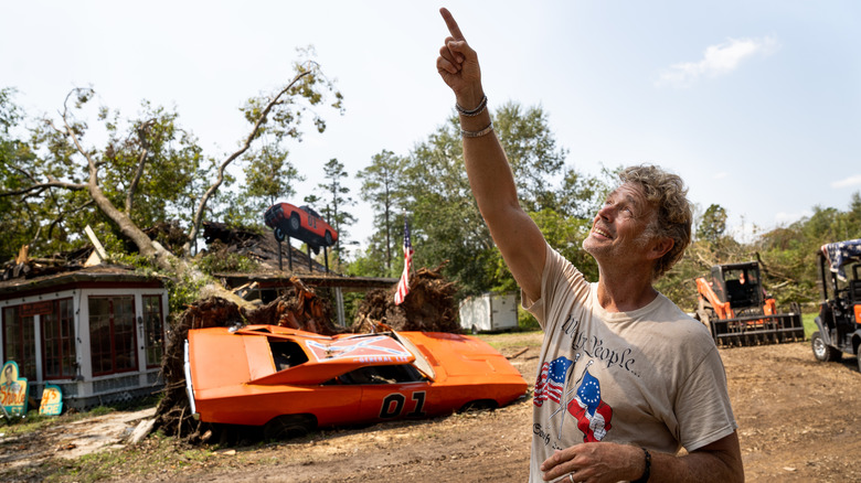 Actor John Schneider (Bo Duke) in "The Dukes of Hazzard" points to where a tree snapped and landed on the roof of a General Lee at his studios during Hurricane Ida.