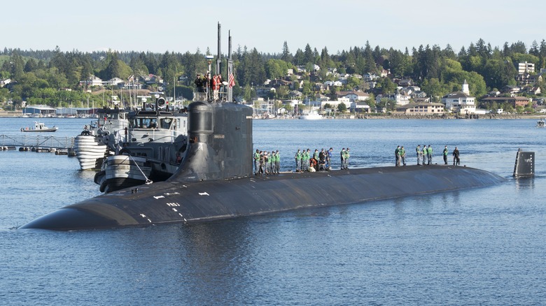 USS Seawolf sitting in a harbor with crew members walking along its hull.