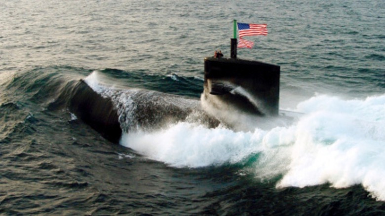 An American submarine sailing along the surface of the water, flying American flags.