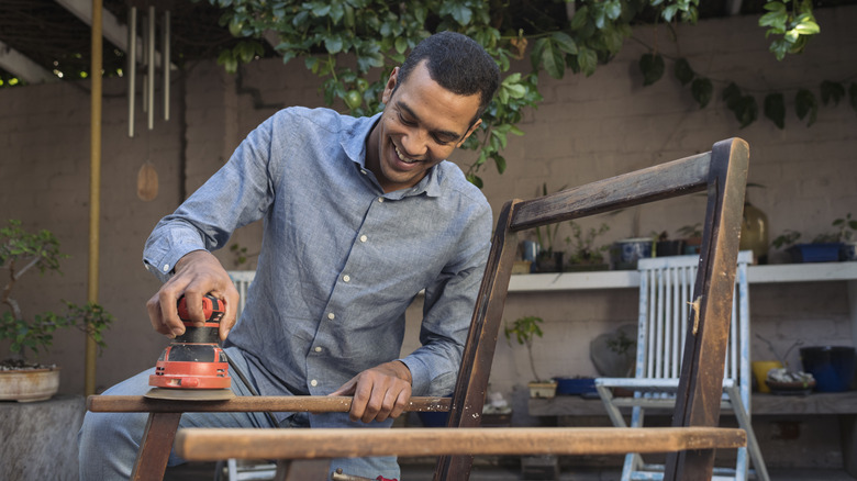 man using sander on chair frame